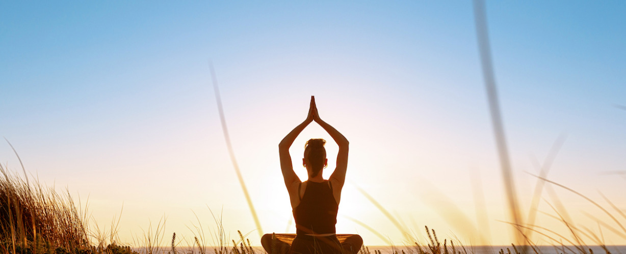 Silhouette meditation girl on the background of the stunning sea and sunset.